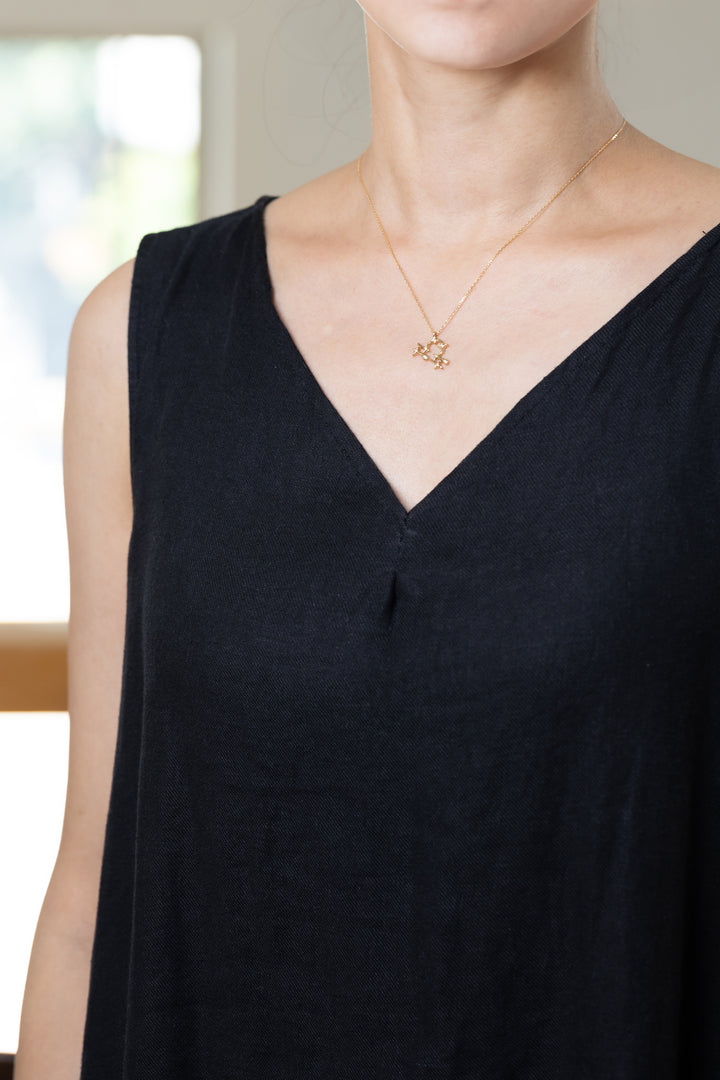 An Libra necklace that shines at the neckline of a black dress.