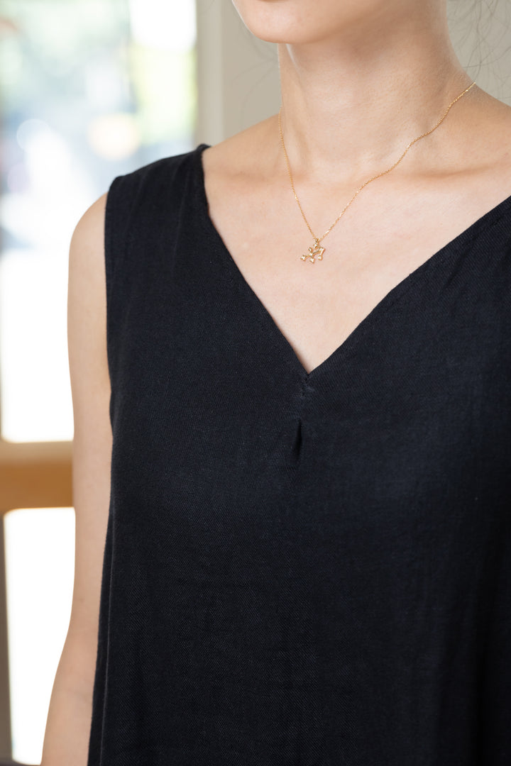 An Sagittarius necklace that shines at the neckline of a black dress.