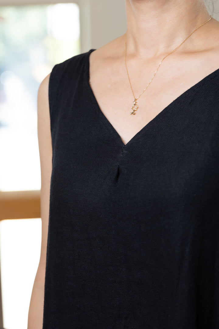 An Capricorn necklace that shines at the neckline of a black dress.