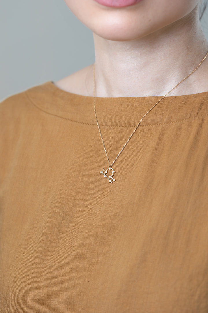 A gold Libra necklace that matches brown clothes.