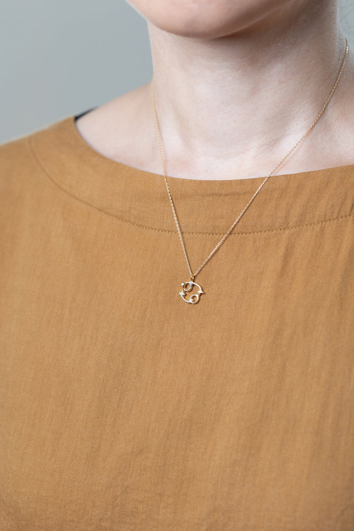A gold Cancer necklace that matches brown clothes.